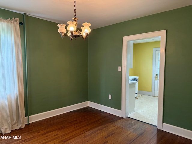 unfurnished room with a notable chandelier, baseboards, and wood finished floors