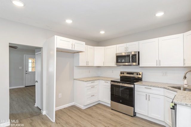 320 2nd Ave, Altoona, PA 16602 - kitchen featuring light stone countertops, light wood finished floors, a sink, appliances with stainless steel finishes, and white cabinetry