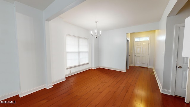 unfurnished room featuring a chandelier, wood-type flooring, and baseboards