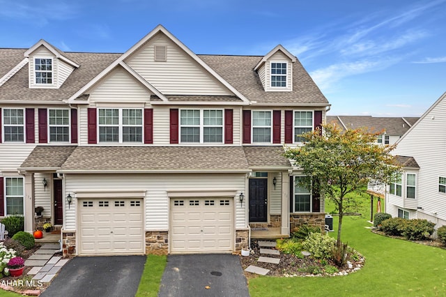 townhome / multi-family property with driveway, a garage, stone siding, roof with shingles, and a front lawn