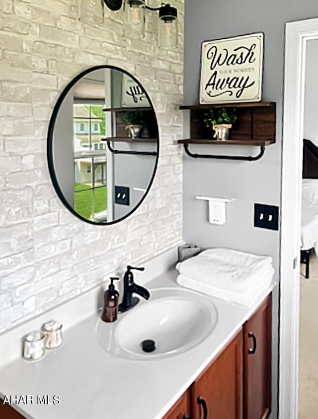 ensuite bathroom with brick wall, connected bathroom, and vanity