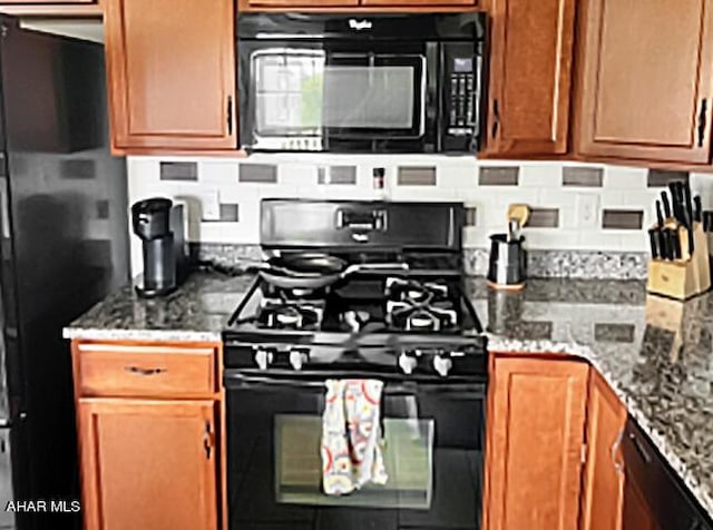 kitchen with black appliances, stone counters, backsplash, and brown cabinetry