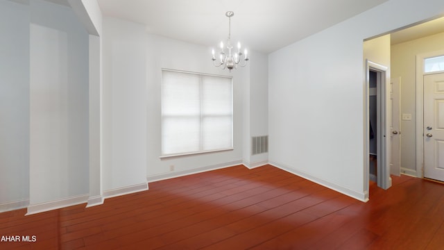 spare room featuring a chandelier, visible vents, baseboards, and hardwood / wood-style flooring