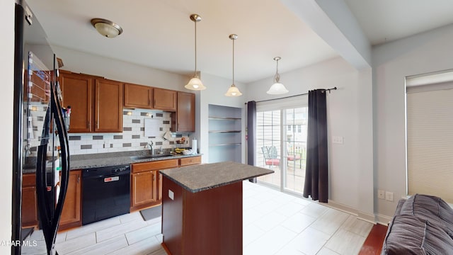 kitchen featuring dark countertops, backsplash, brown cabinetry, a sink, and black appliances