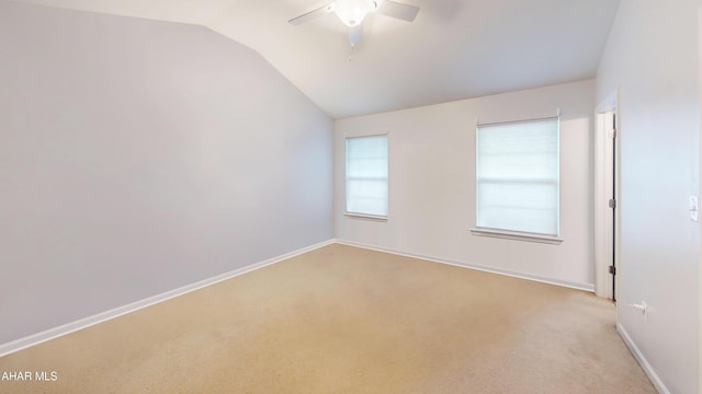 spare room featuring a ceiling fan, light carpet, vaulted ceiling, and baseboards