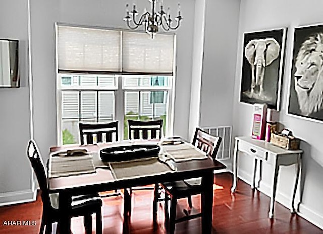 dining space with an inviting chandelier, baseboards, and wood finished floors