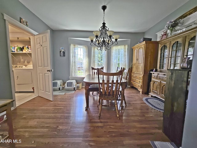 dining area featuring separate washer and dryer, a chandelier, and dark wood-style floors