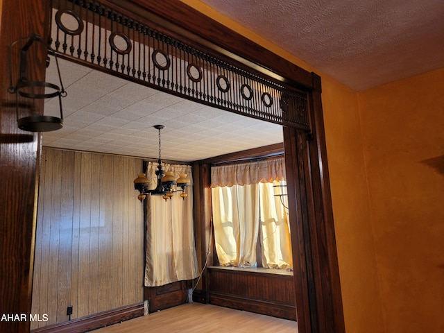 interior space featuring wooden walls, a notable chandelier, and hardwood / wood-style flooring