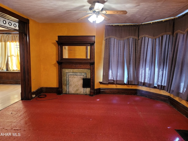 unfurnished living room with ceiling fan and a textured ceiling