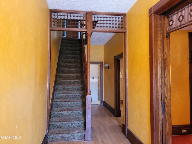 stairs featuring a textured ceiling and hardwood / wood-style flooring