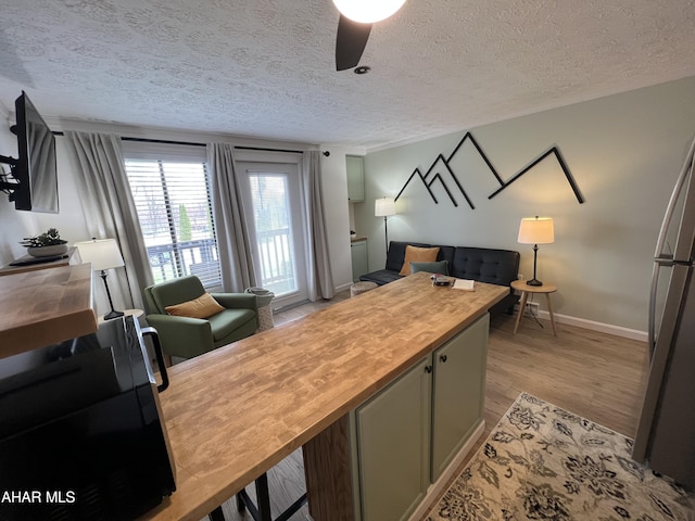 bedroom featuring stainless steel fridge, light hardwood / wood-style flooring, ceiling fan, and a textured ceiling