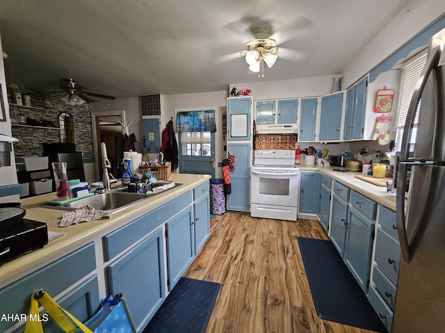 2802 Elm St, Altoona, PA 16601 - kitchen with white electric stove, under cabinet range hood, blue cabinets, ceiling fan, and freestanding refrigerator