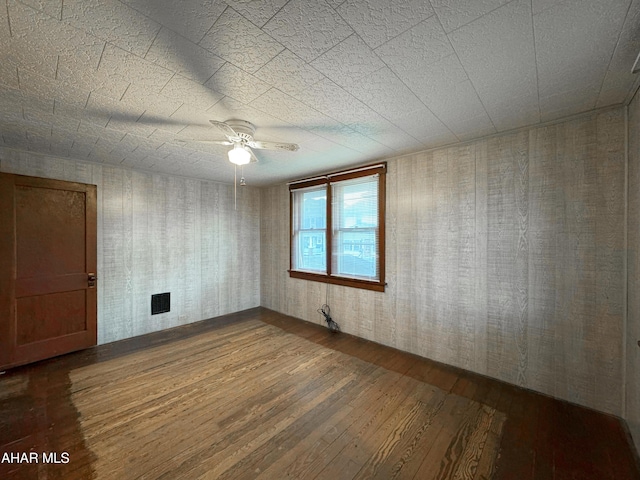 spare room featuring dark wood-type flooring and a ceiling fan