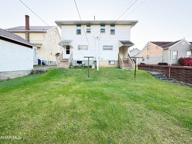 rear view of house featuring entry steps and a lawn