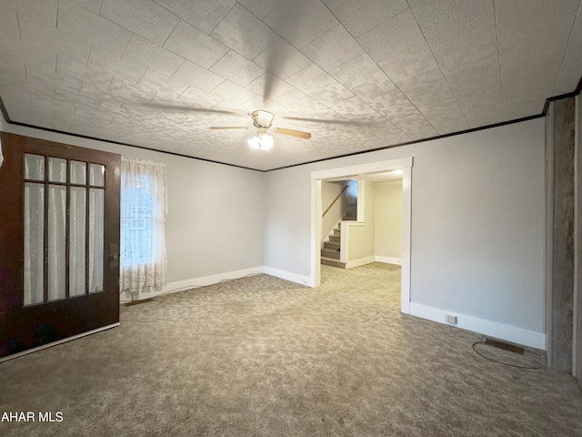 interior space with crown molding, carpet floors, a ceiling fan, and baseboards