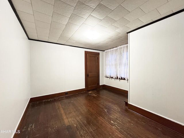 empty room featuring dark wood-type flooring and baseboards