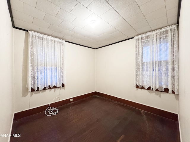 spare room with baseboards and dark wood-style flooring