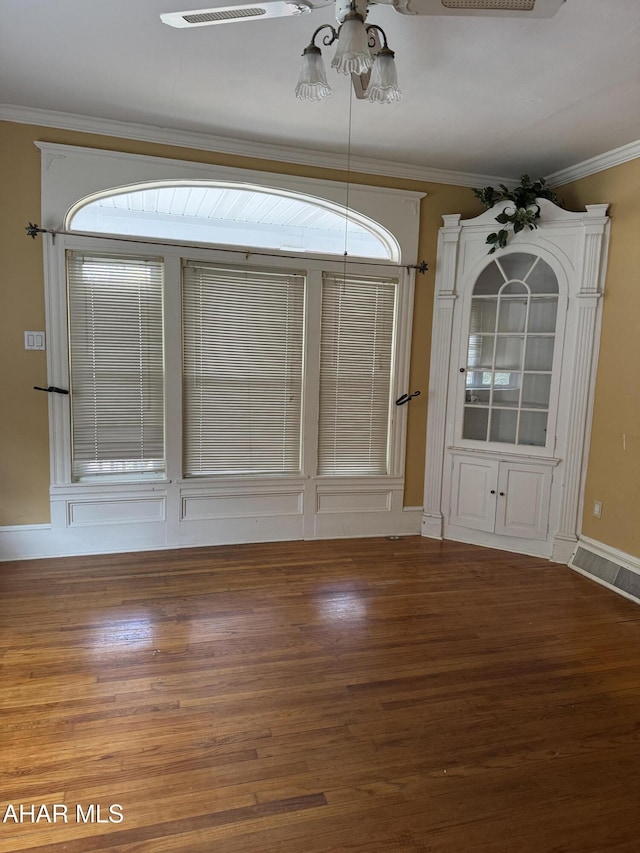 unfurnished dining area with ornamental molding, ceiling fan, baseboards, and wood finished floors