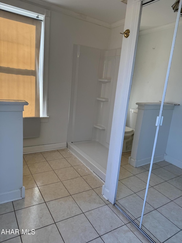 bathroom with tile patterned flooring, toilet, baseboards, ornamental molding, and a stall shower