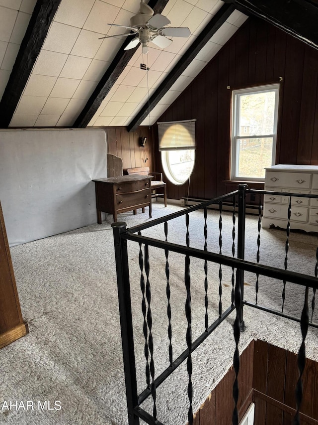 additional living space with vaulted ceiling with beams, wood walls, carpet, and a ceiling fan