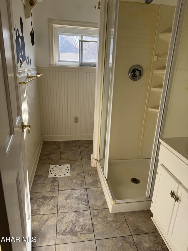 bathroom featuring a wainscoted wall, a stall shower, vanity, and tile patterned floors