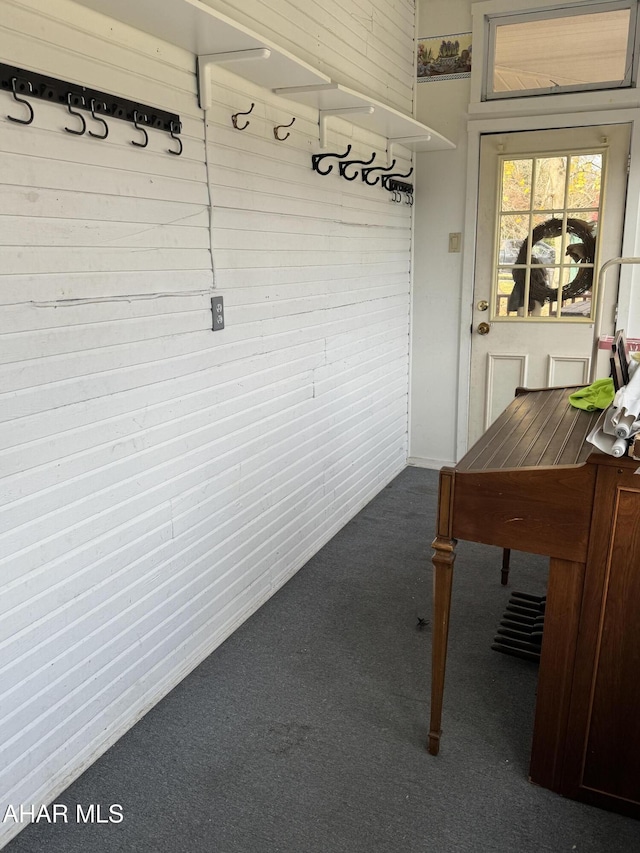 mudroom with dark colored carpet and wood walls