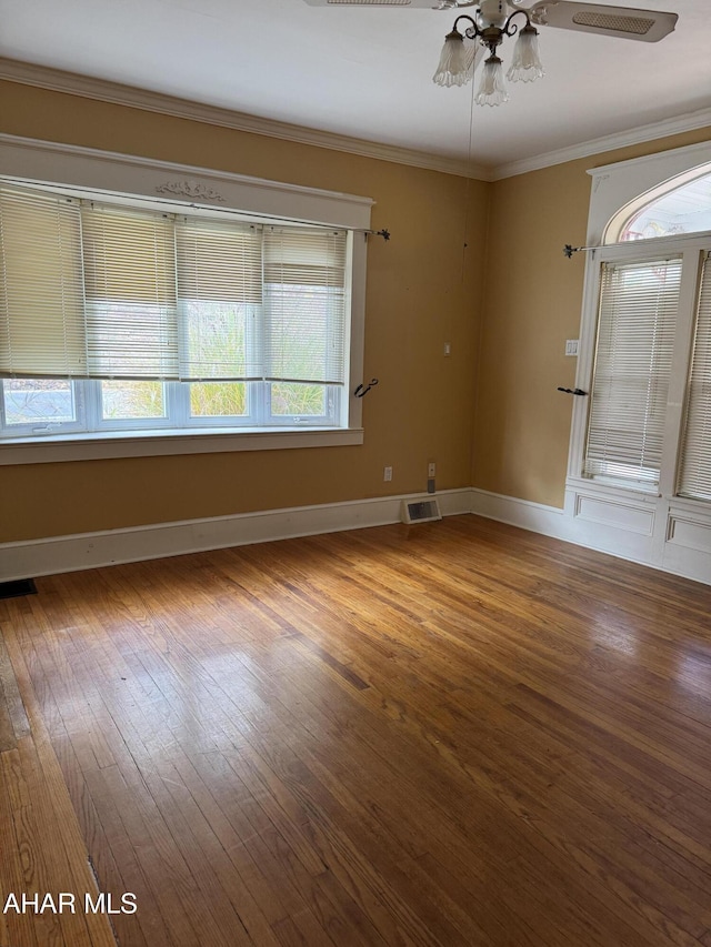 empty room featuring visible vents, crown molding, and wood finished floors