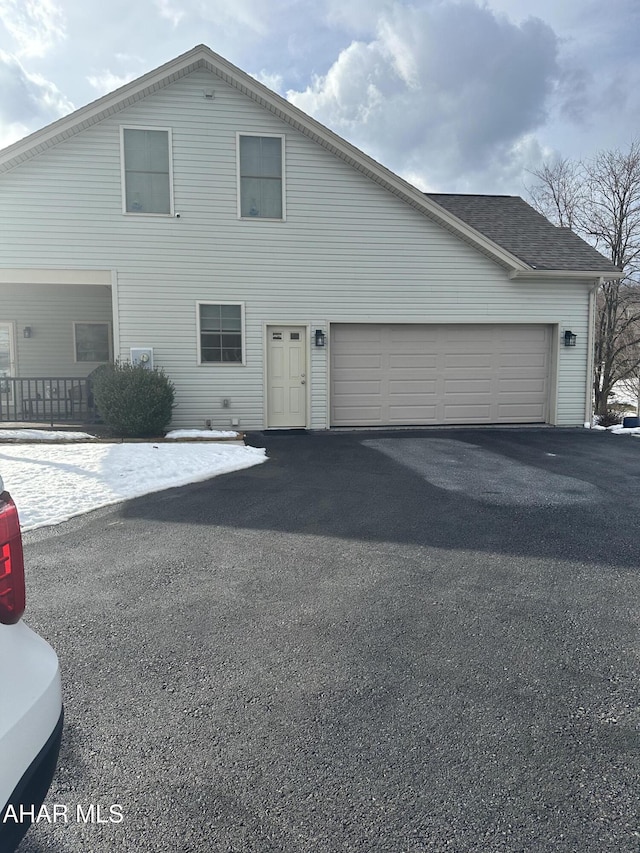 traditional home featuring a garage, aphalt driveway, and a shingled roof