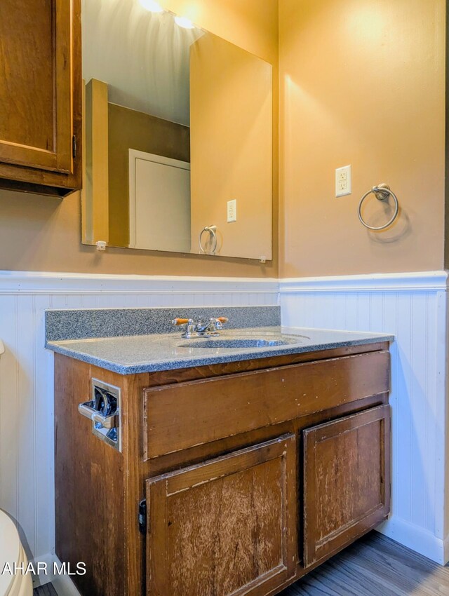 151 Rio Grande Rd, Clearville, PA 15535 - half bath with a wainscoted wall, vanity, a decorative wall, toilet, and wood finished floors