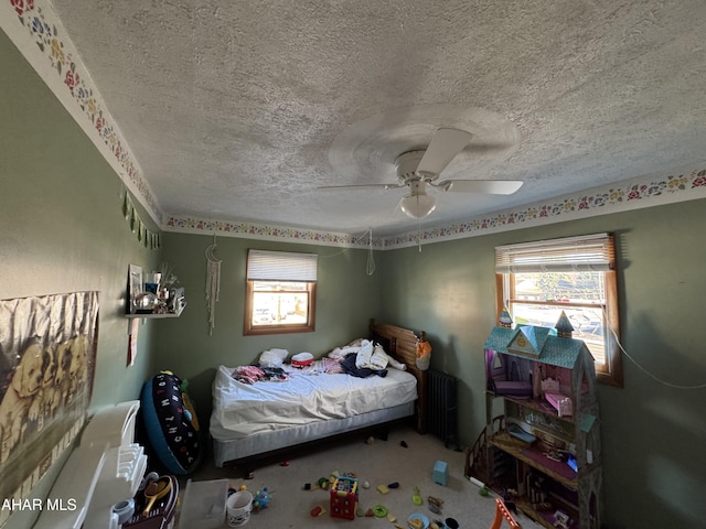 bedroom with radiator heating unit, a textured ceiling, multiple windows, and ceiling fan