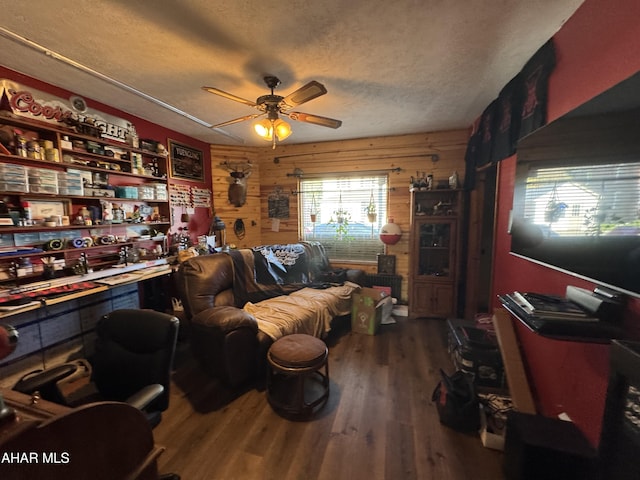 living room with wood walls, ceiling fan, a textured ceiling, and hardwood / wood-style flooring