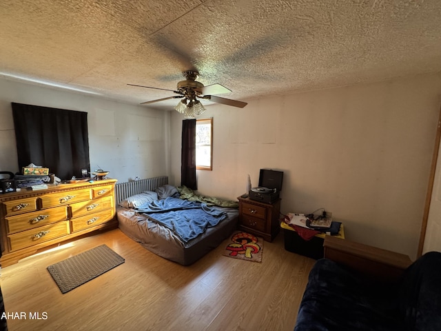 bedroom featuring hardwood / wood-style flooring, ceiling fan, and a textured ceiling