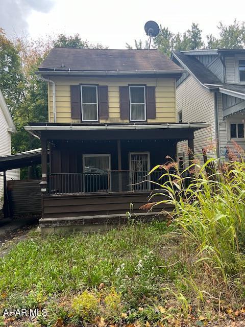 back of property with covered porch and a carport