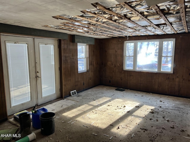 unfurnished room featuring french doors and wood walls