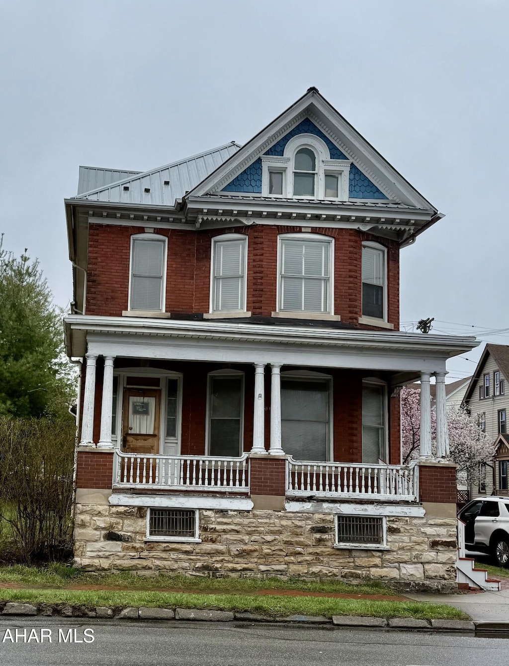 view of front of house featuring brick siding, a porch, and metal roof