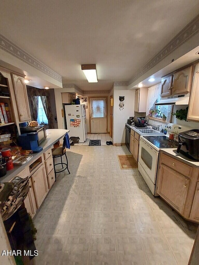 kitchen featuring light brown cabinetry, sink, white appliances, and a breakfast bar area