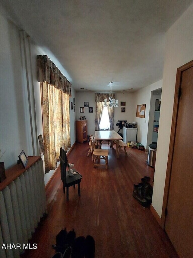 dining area featuring a chandelier, radiator heating unit, and dark hardwood / wood-style flooring