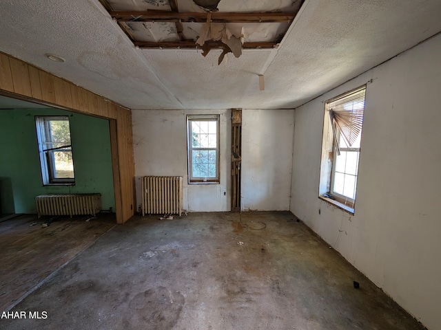 miscellaneous room with radiator, concrete flooring, and a textured ceiling