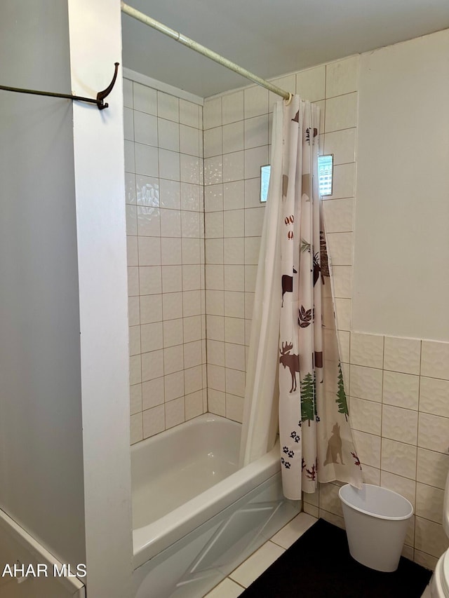 bathroom featuring tile patterned flooring, toilet, tile walls, and shower / tub combo with curtain