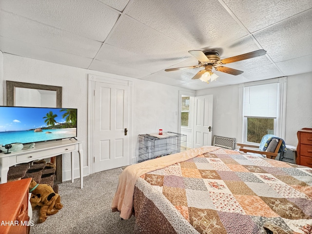 carpeted bedroom with a paneled ceiling and ceiling fan