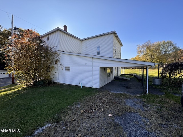 view of side of property with a carport and a lawn