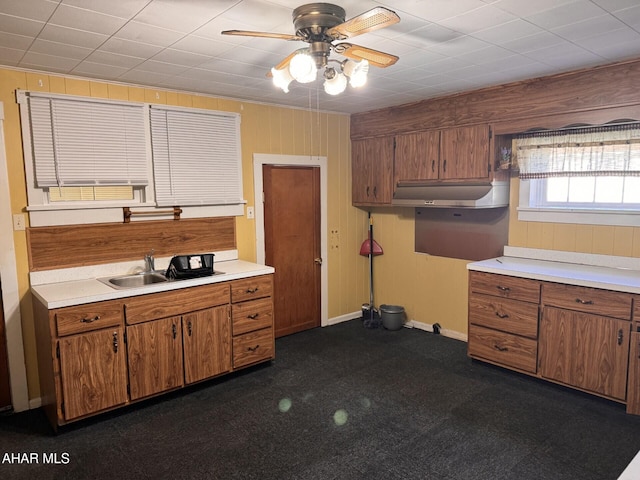 kitchen with ceiling fan, wooden walls, and sink