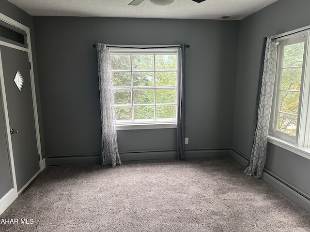 empty room featuring carpet flooring, ceiling fan, and a healthy amount of sunlight