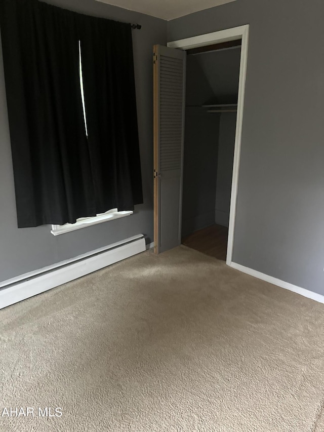 unfurnished bedroom with carpet flooring, a closet, and baseboard heating