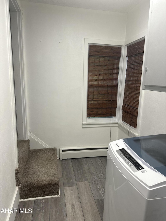 interior space with dark wood-type flooring, a baseboard radiator, and washer / dryer