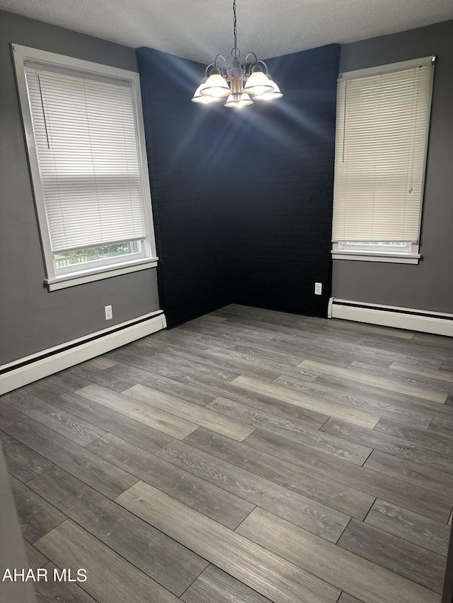 unfurnished room with a textured ceiling, light hardwood / wood-style flooring, a chandelier, and a baseboard radiator