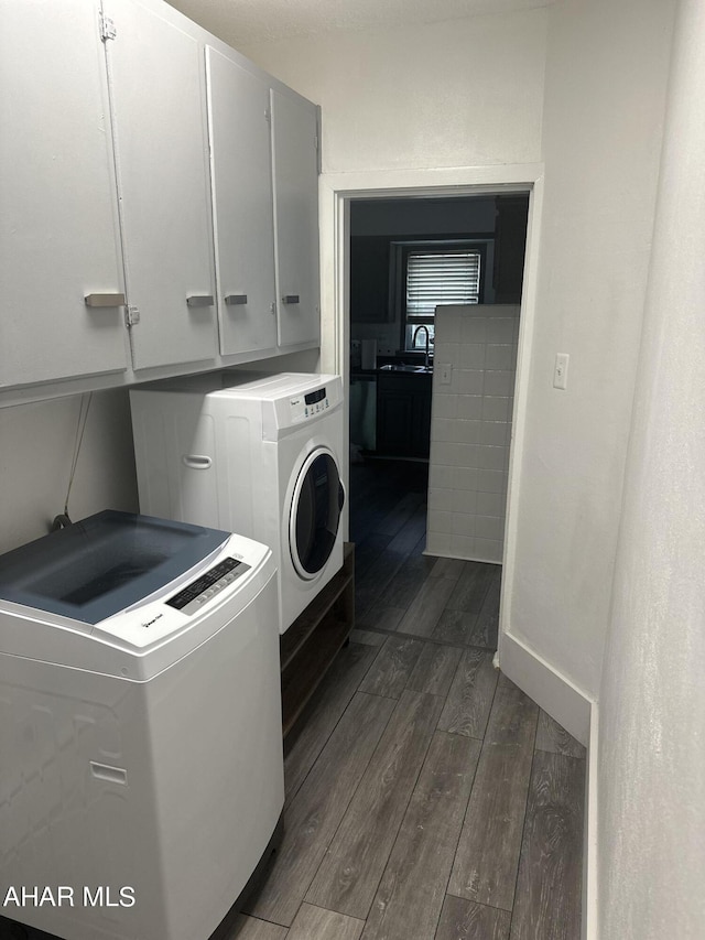 laundry room featuring sink, washer and dryer, cabinets, and dark wood-type flooring