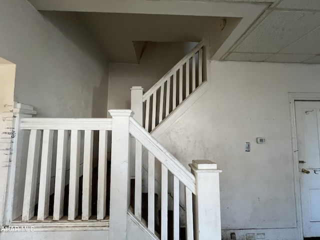 stairway featuring a drop ceiling