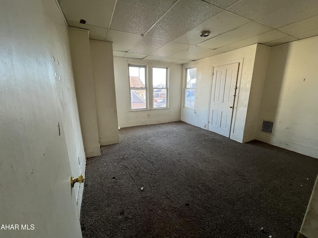 carpeted empty room with a drop ceiling