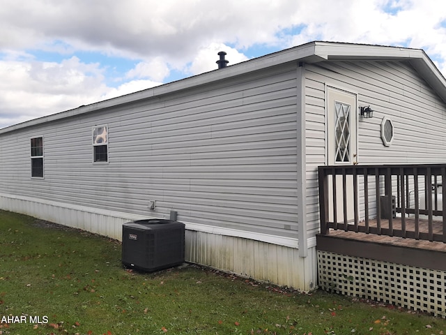 view of side of property featuring central AC, a lawn, and a wooden deck